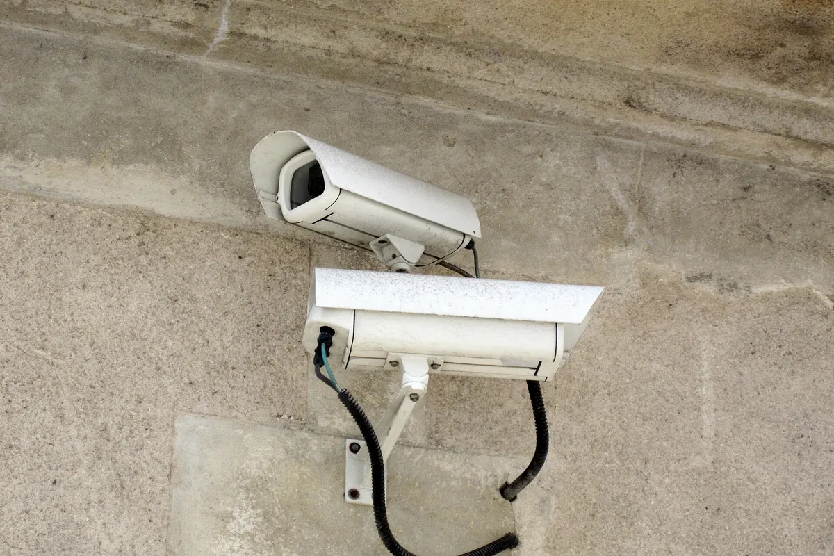 Dwie tubowe kamery monitoringu na ścianie budynku